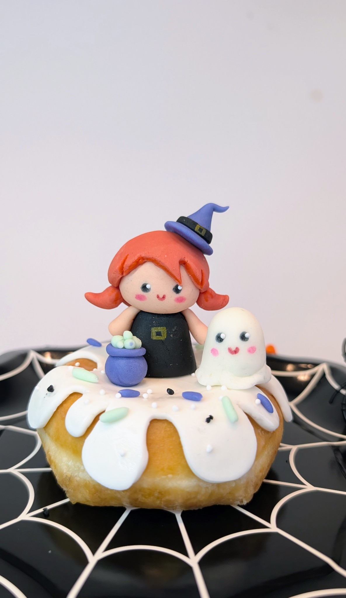 Brujita con caldero sobre donut decorado para Halloween