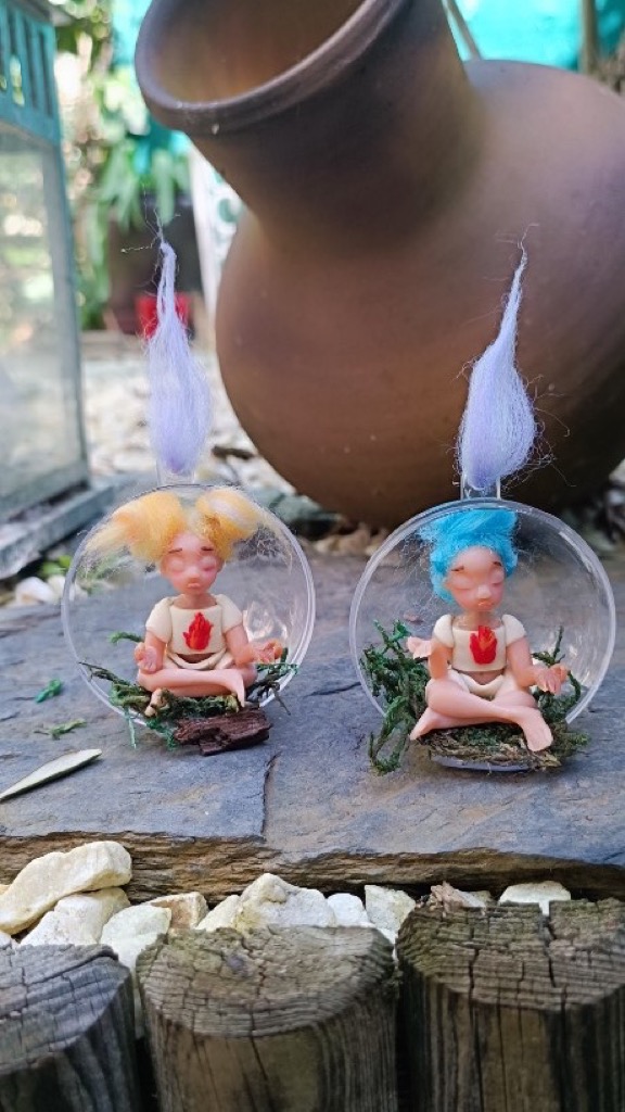 Dos figuras meditando dentro de esferas transparentes con pelo amarillo y azul