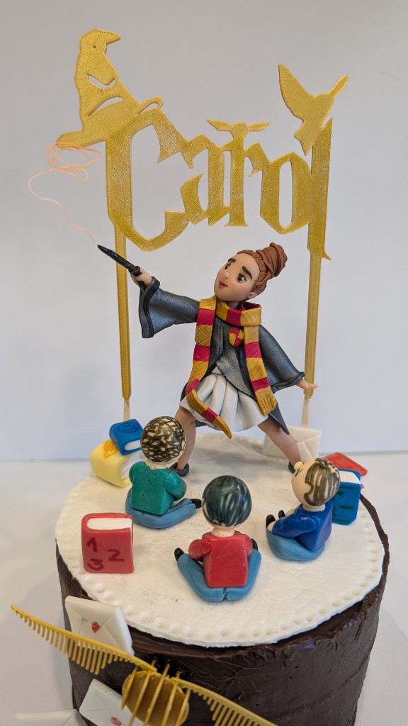 Topper de tarta Harry Potter: alumna con varita, letras doradas y niños en porcelana fría
