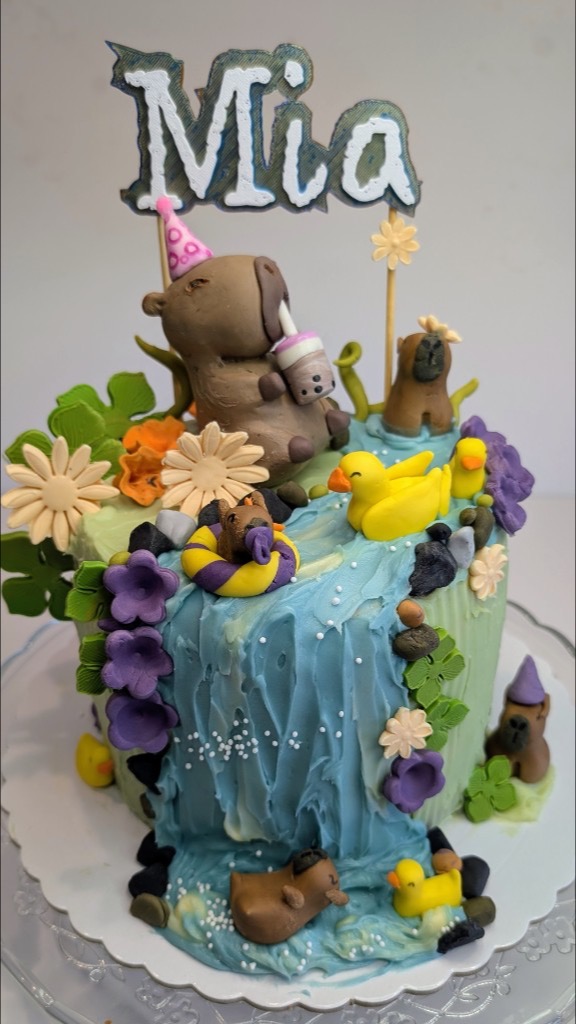 Tarta temática capibaras con cascada, flotador, flores y gorros de fiesta en porcelana fría