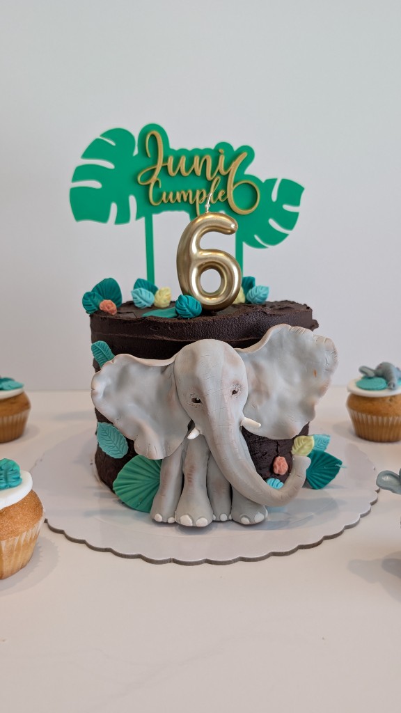 Tarta de chocolate con elefante de fondant, hojas tropicales y topper cumpleaños
